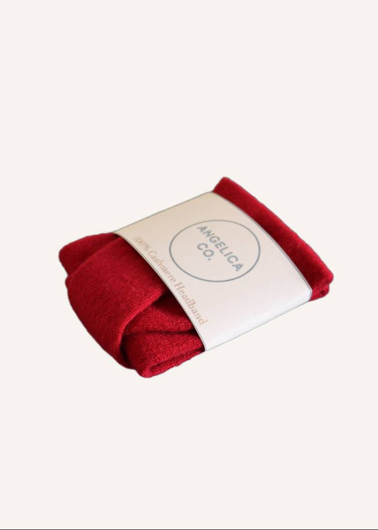 Red cashmere headband wrapped in a white cardboard wrapper