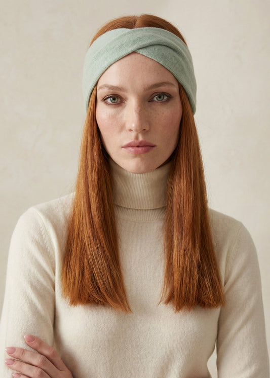 Woman wearing a light green headband against a plain background