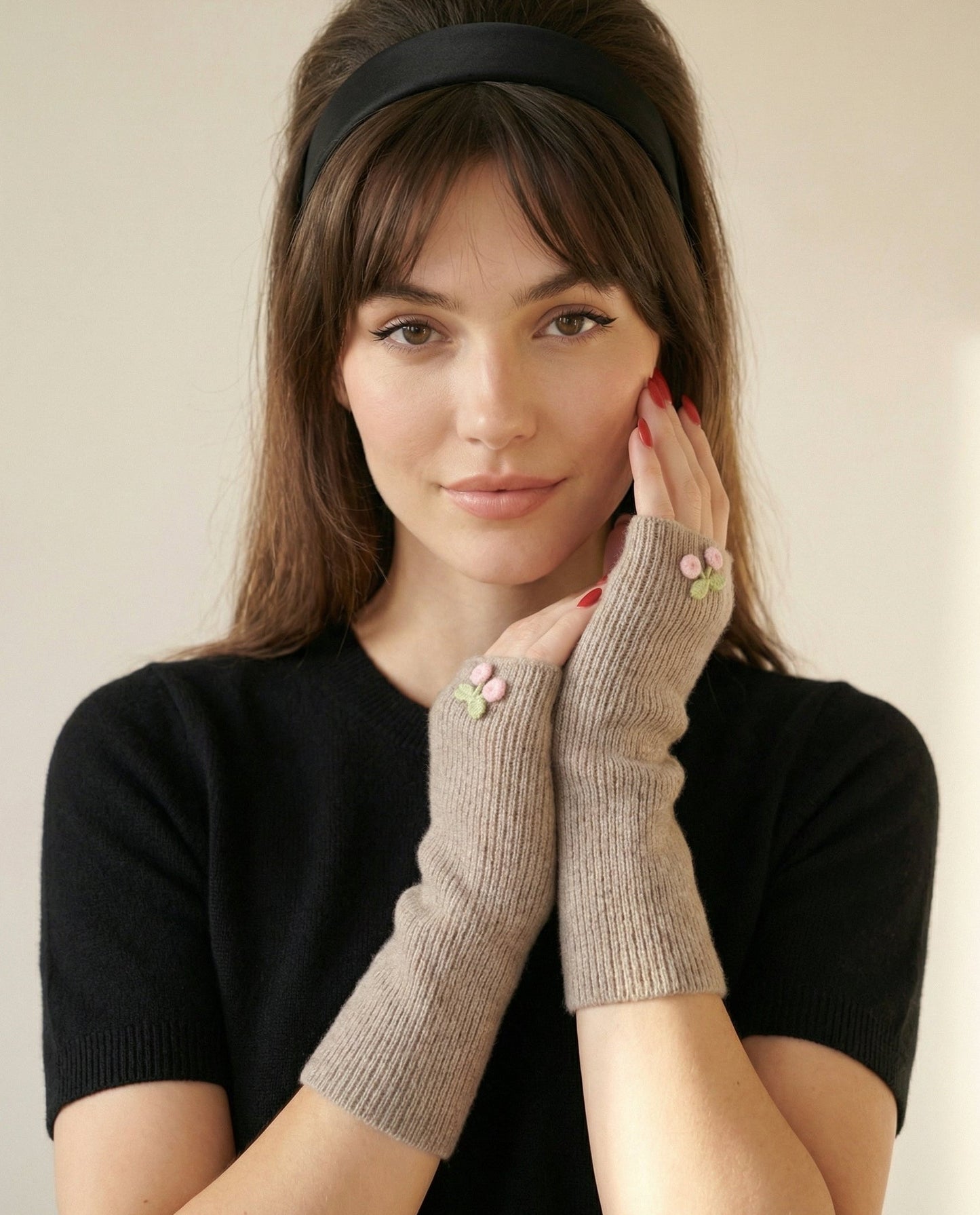 Woman wearing gray fingerless gloves with buttons against a plain background