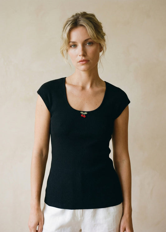 Woman wearing a black top with a red brooch against a beige background