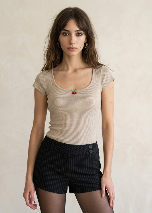 Woman wearing a beige top and black shorts with a plain background