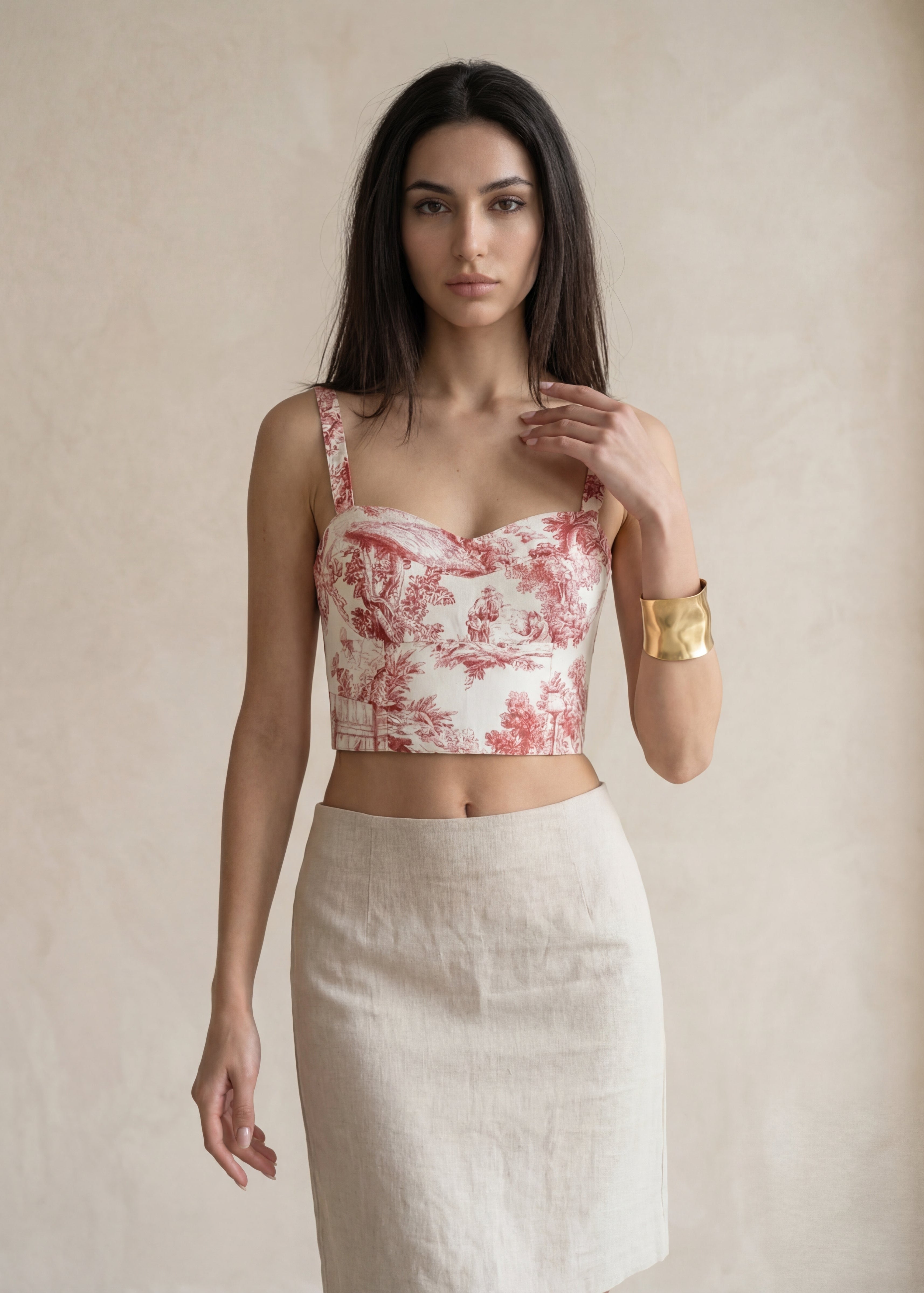 Woman wearing a red and white floral top with a beige background