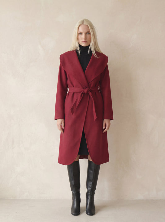 Woman wearing a red coat and black boots against a beige background