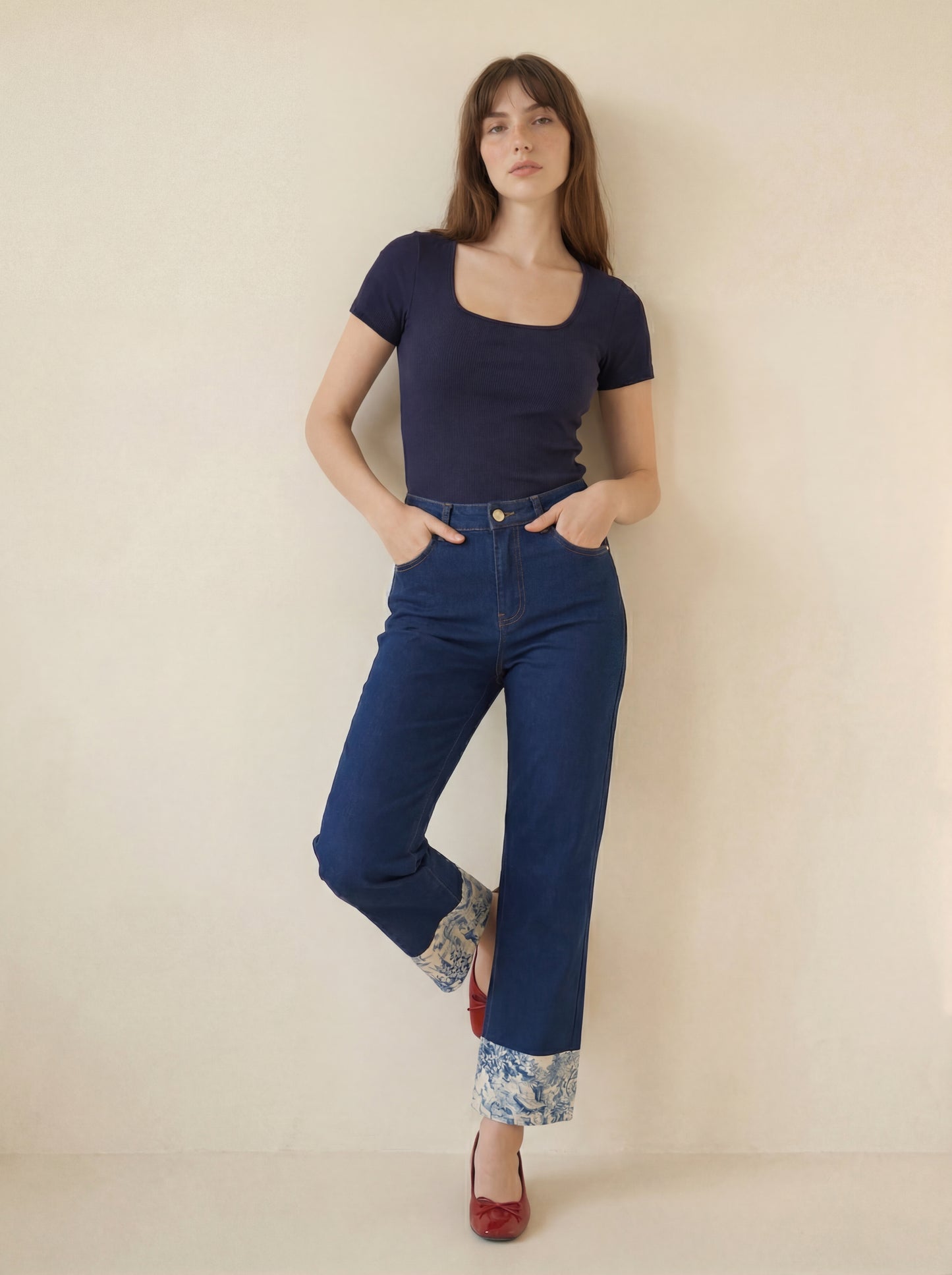 Woman wearing a navy top and blue jeans against a beige background