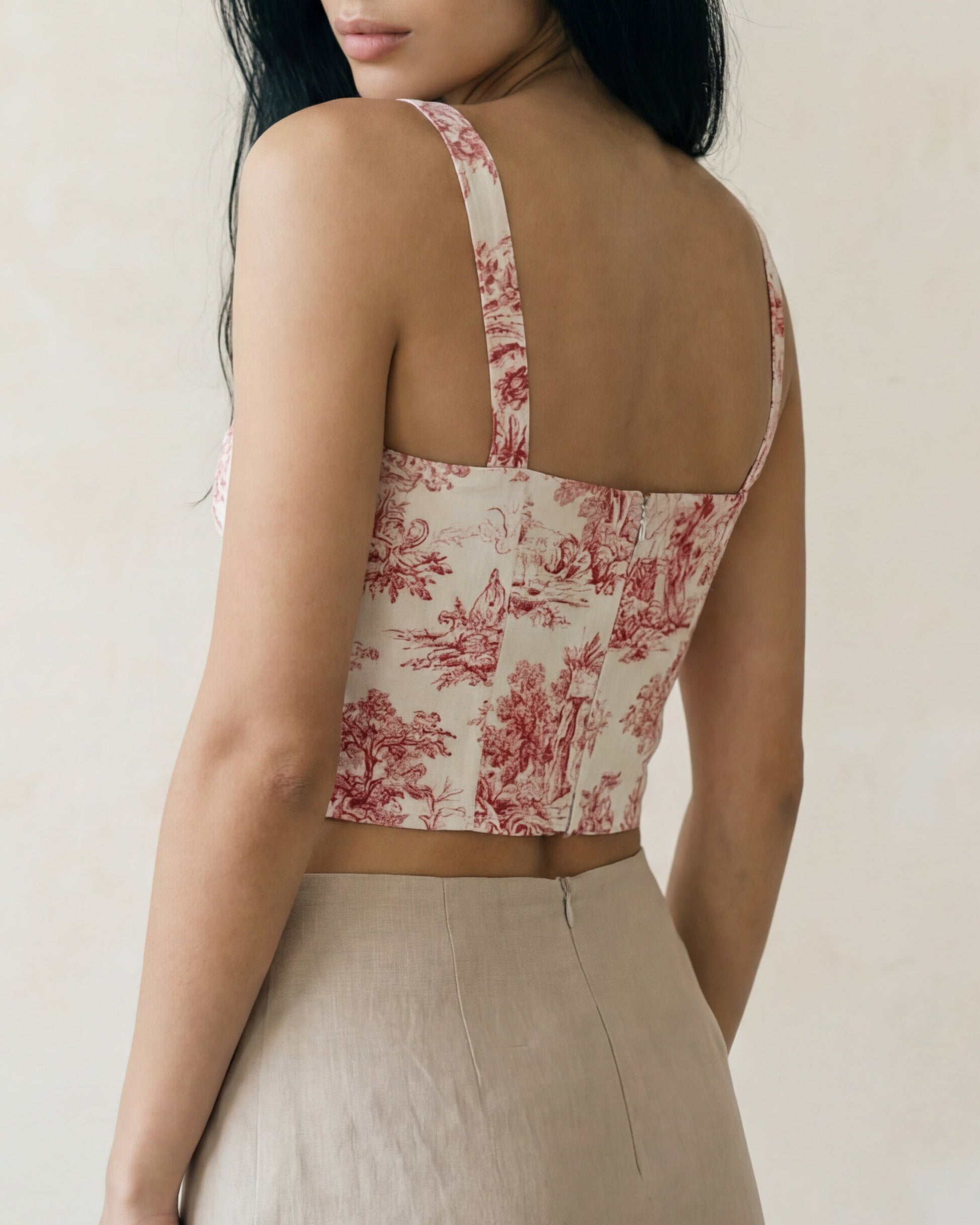 Woman wearing a floral crop top and beige pants against a plain background