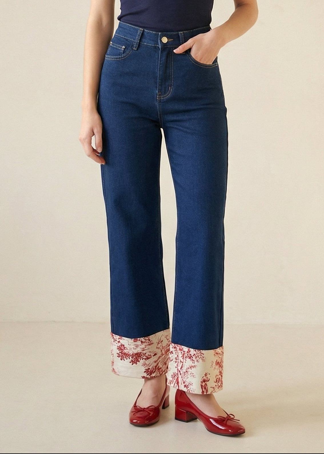 Person wearing blue jeans with floral cuffs on a beige background