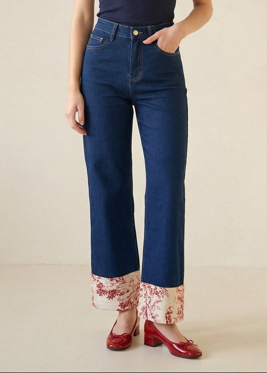 Person wearing blue jeans with floral cuffs on a beige background