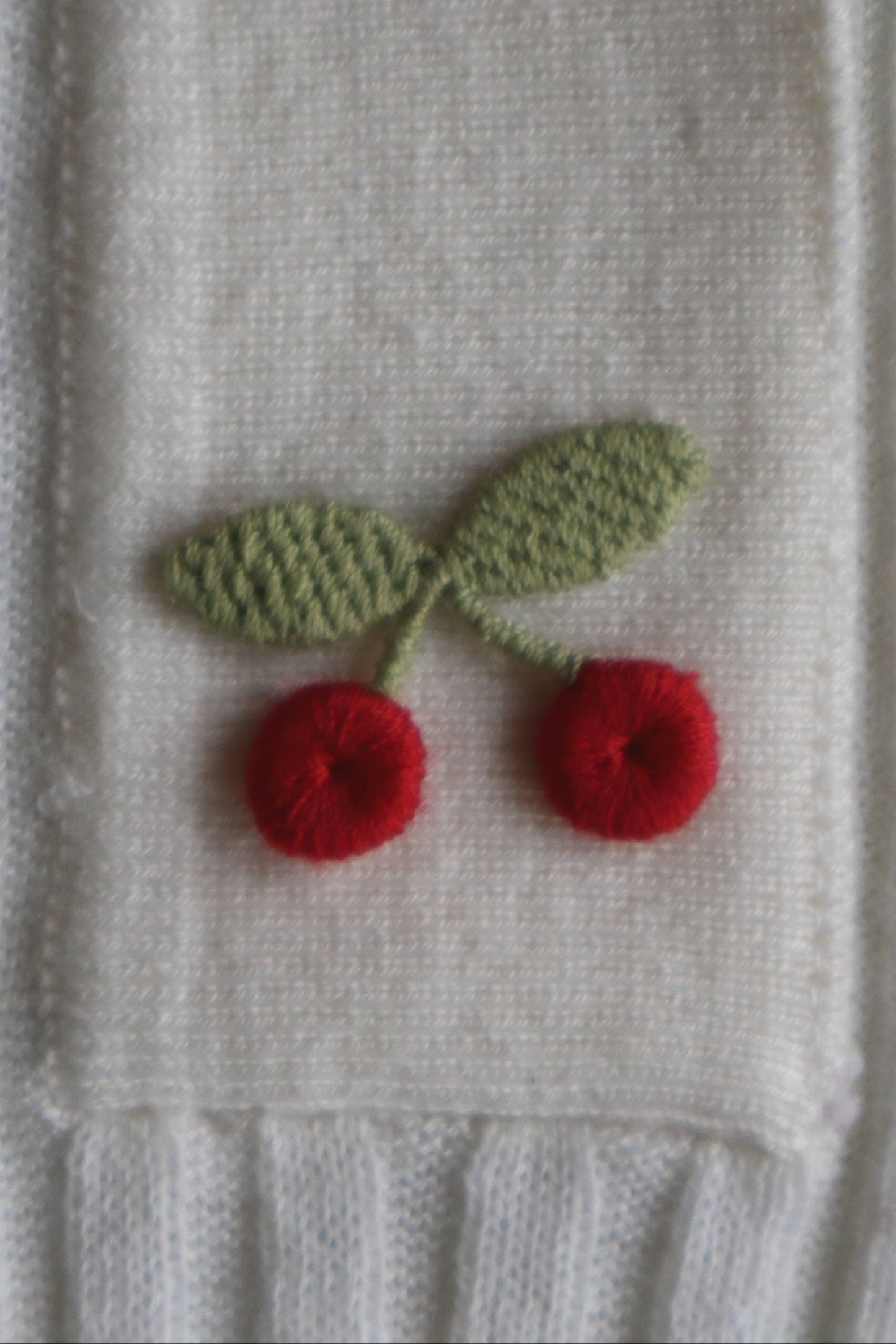 Embroidered cherries on a textured fabric background
