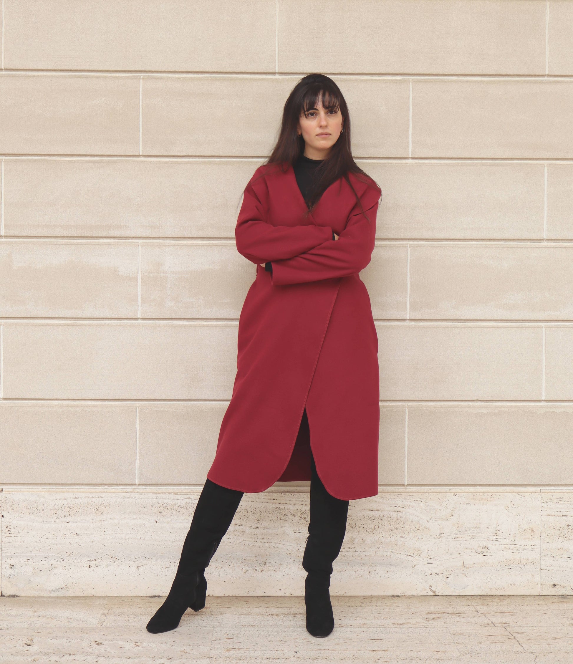 Black haired woman with bangs in red wrap coat and black suede boots