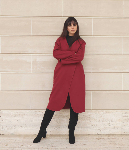Black haired woman with bangs in red wrap coat and black suede boots