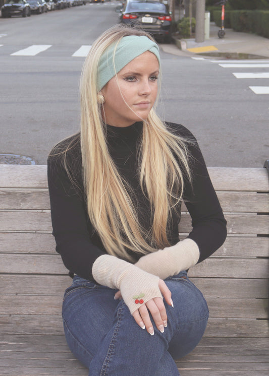 Blonde Woman in a green headband, gold earrings and beige gloves and a black turtleneck