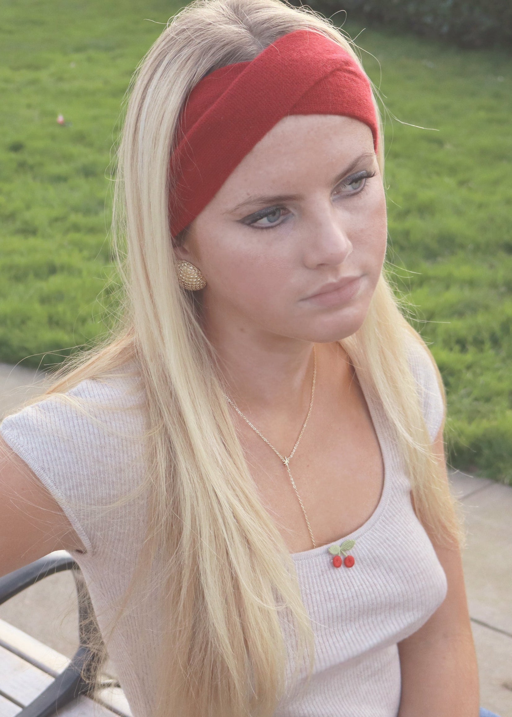 Blonde woman in red headband and beige shirt with cherry embroidery