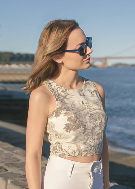 Woman wearing sunglasses and a patterned top by a waterfront