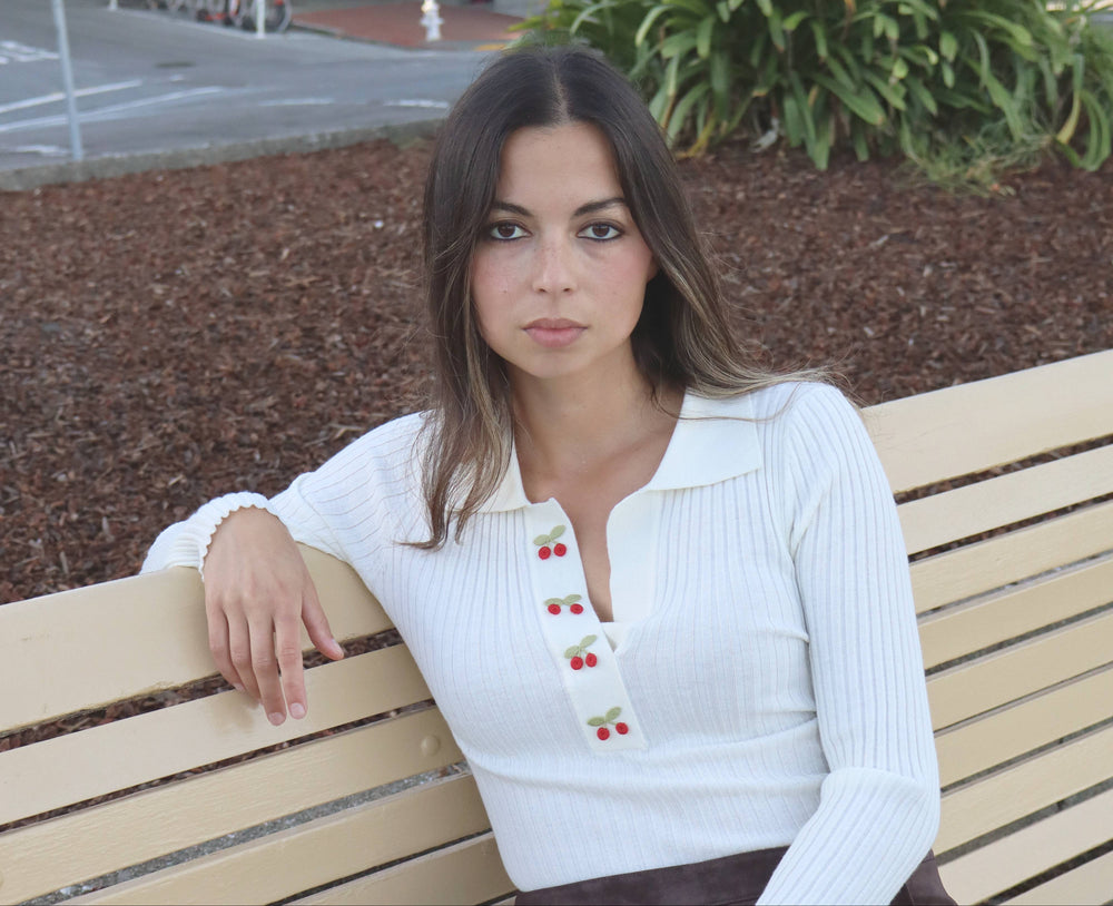 Woman sitting on a bench outdoors with a cityscape background