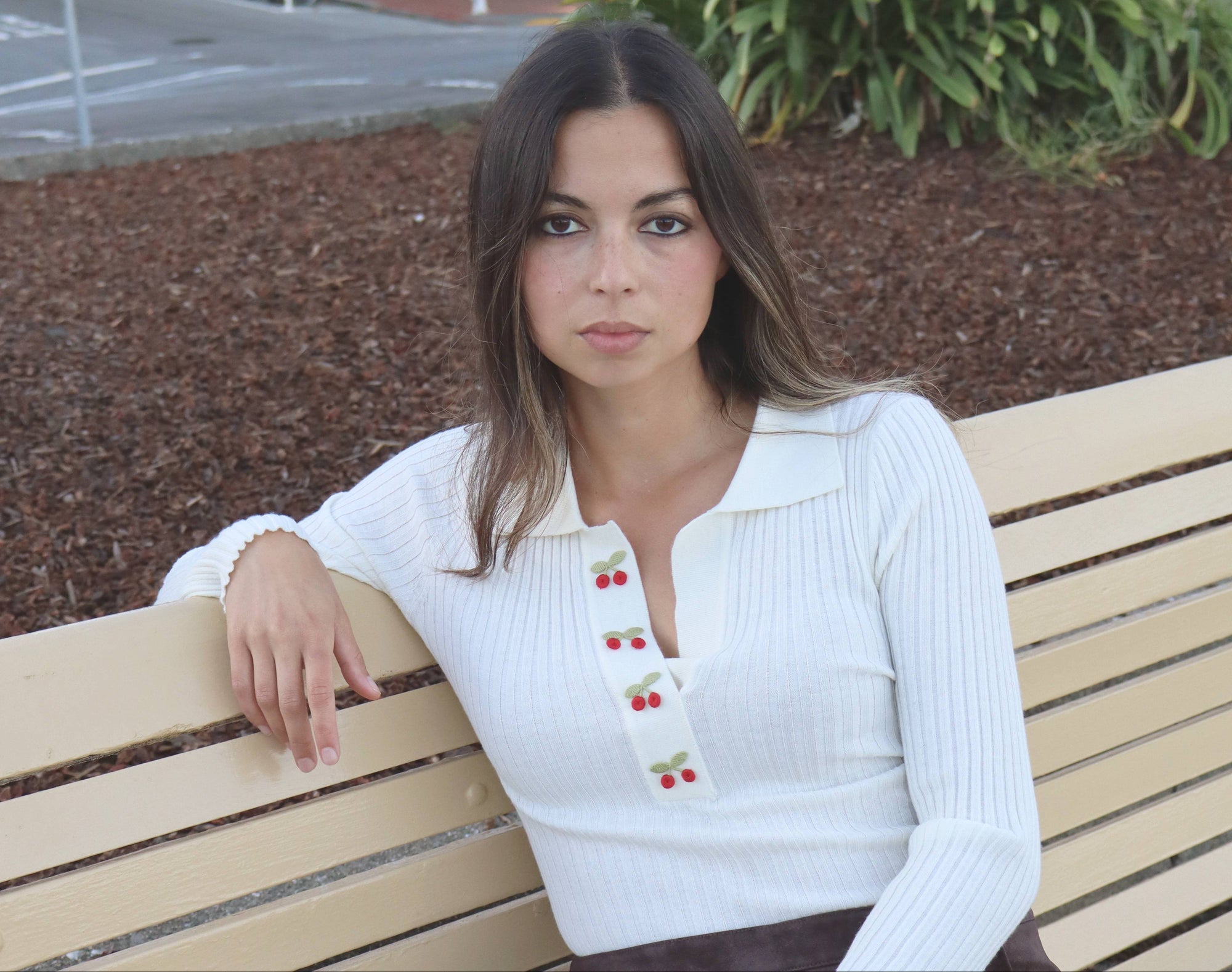 Woman sitting on a bench outdoors with a cityscape background
