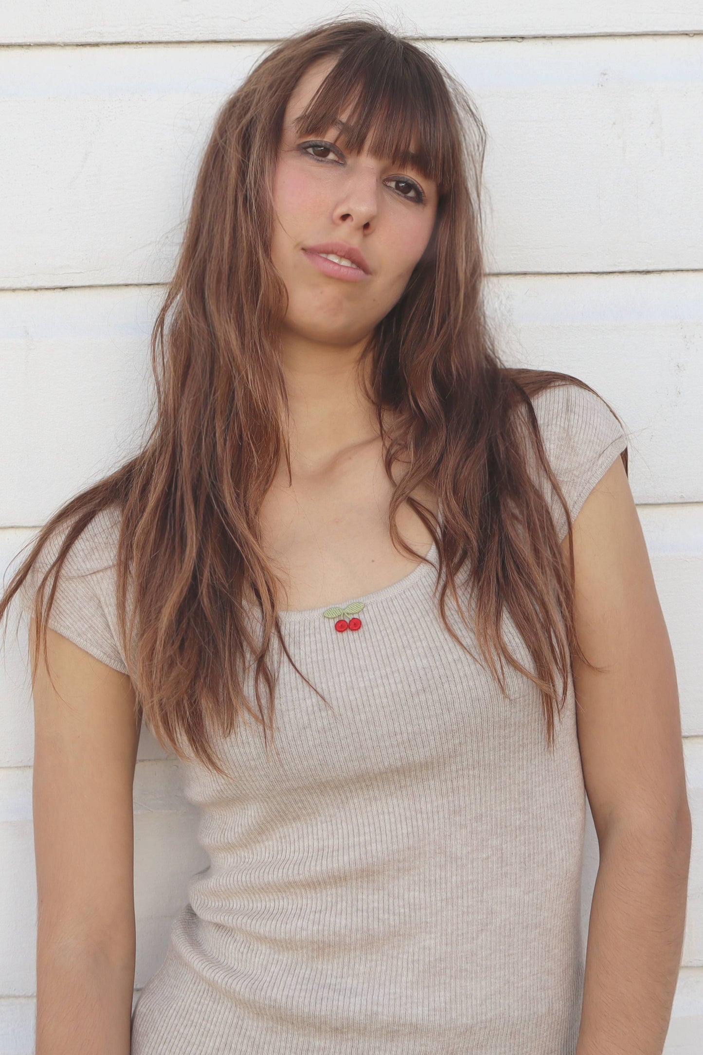 Woman with long hair standing against a light wooden panel background
