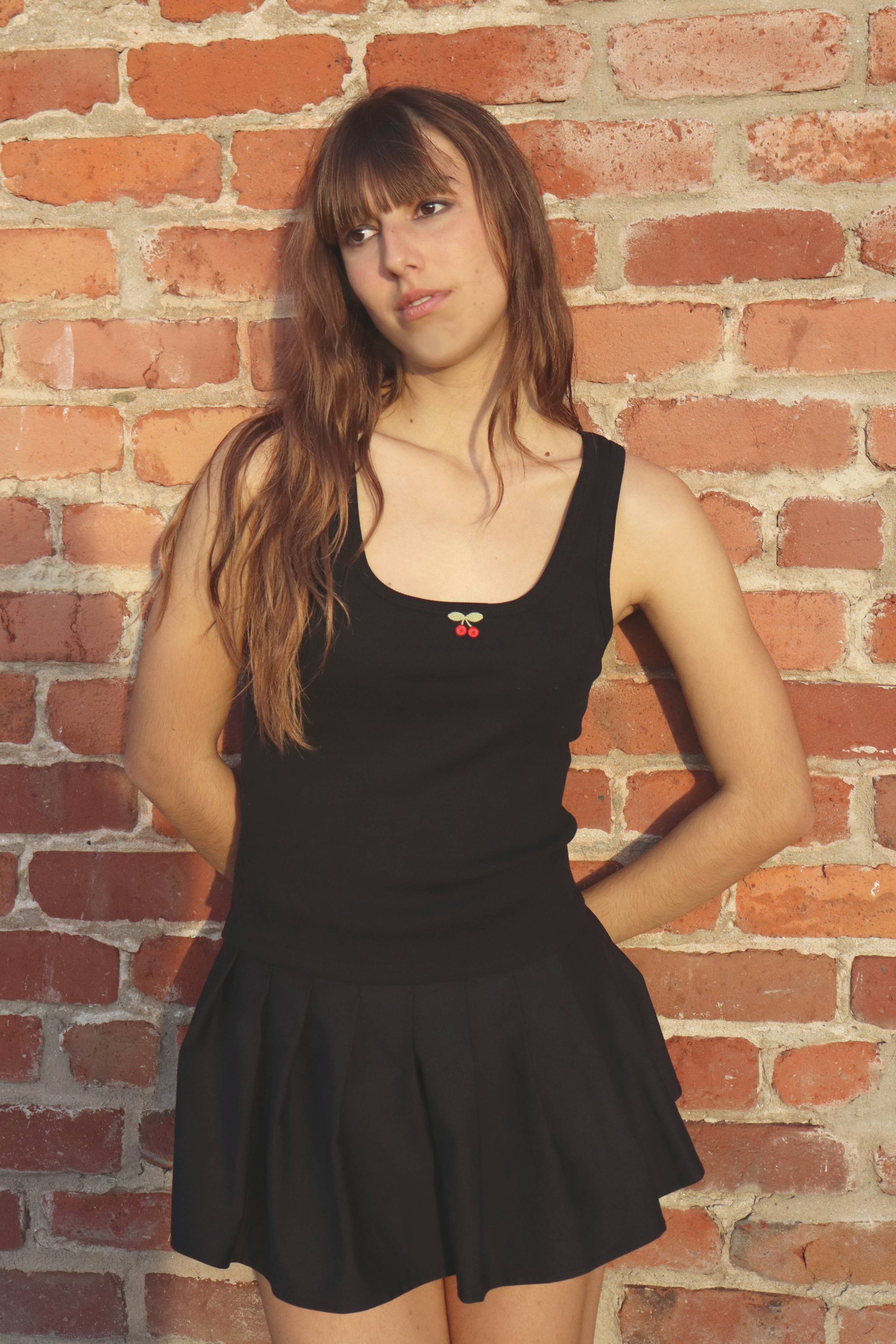 Woman wearing a black dress against a brick wall