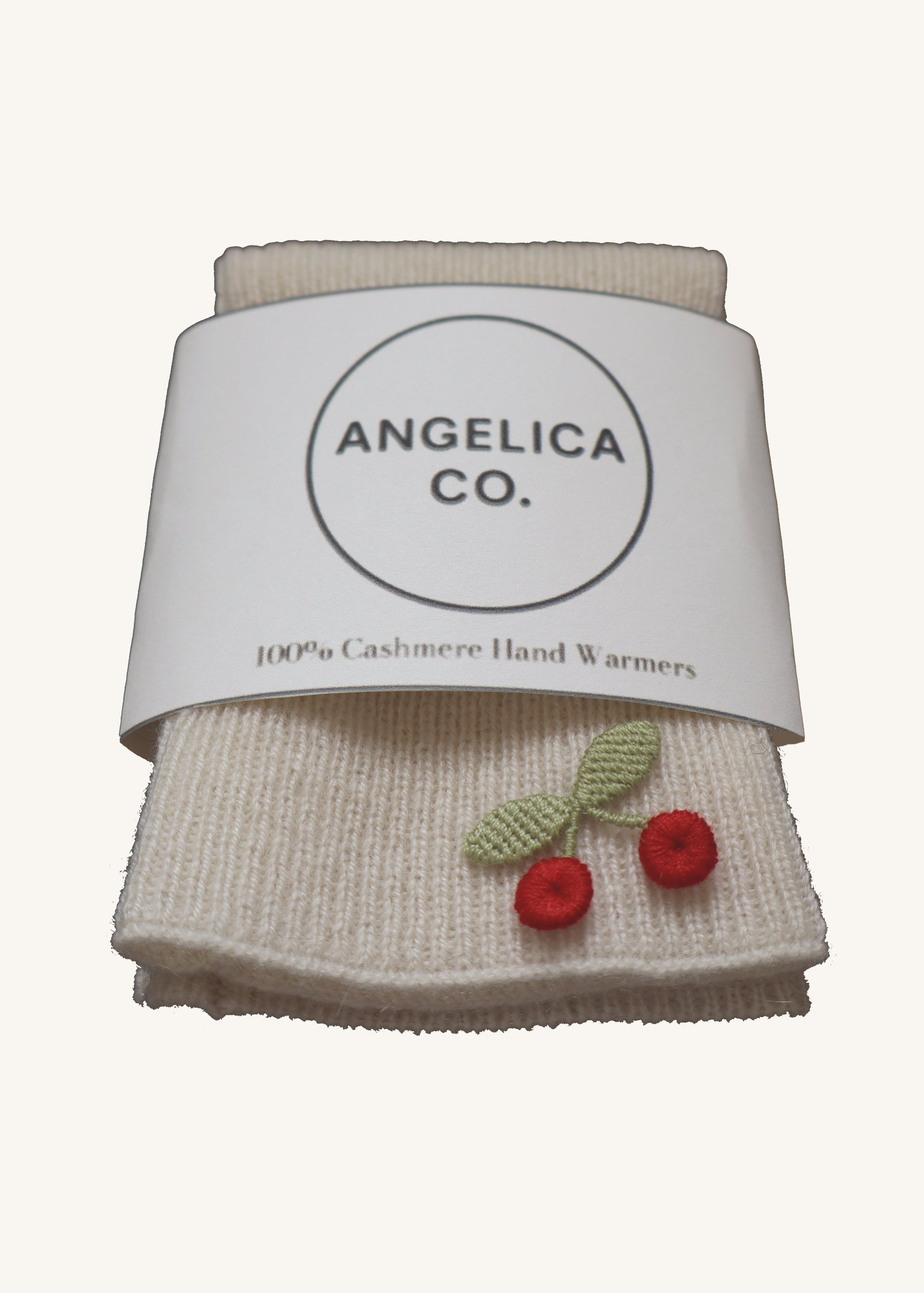 Pair of cashmere hand warmers with cherry designs on a white background, branded 'Angelica Co'.